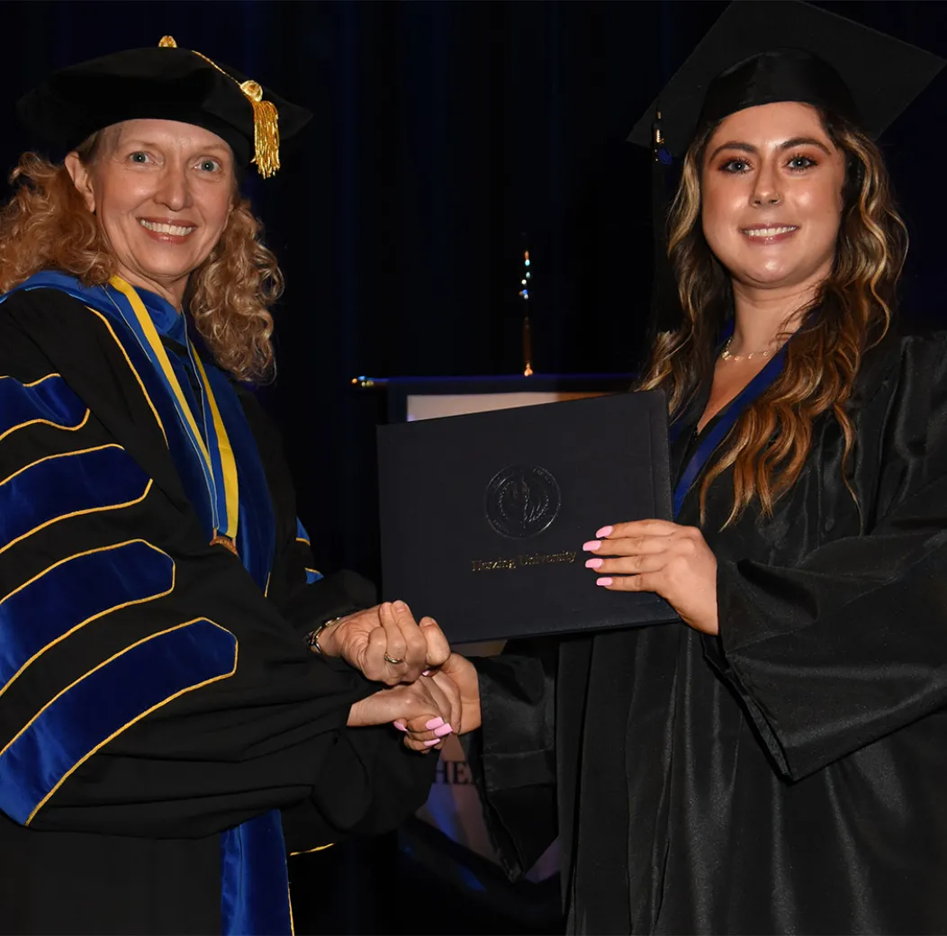 Herzing grad receives her diploma from University president Renee Herzing
