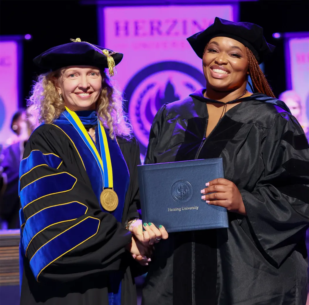    Doctor of Behavioral Health graduate receiving diploma during Herzing University commencement ceremony