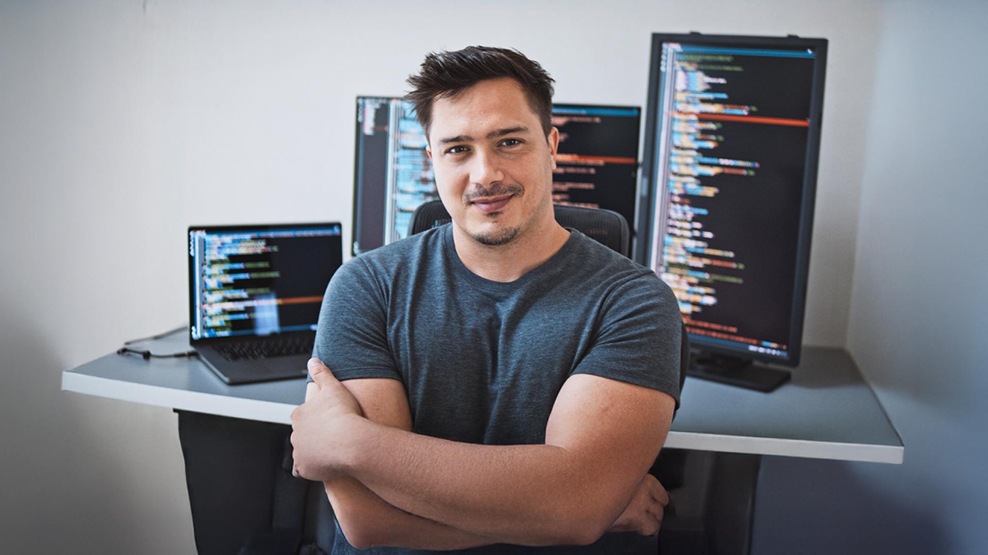 A confident programmer seated in a modern office with coding displayed on dual monitors, reflecting the professional environment of computer science careers.