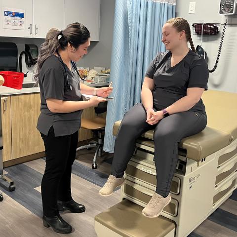 Herzing University ASN (Associate of Science in Nursing) students practicing clinical skills in a healthcare training lab, wearing scrubs and using medical equipment in a realistic hospital setting.